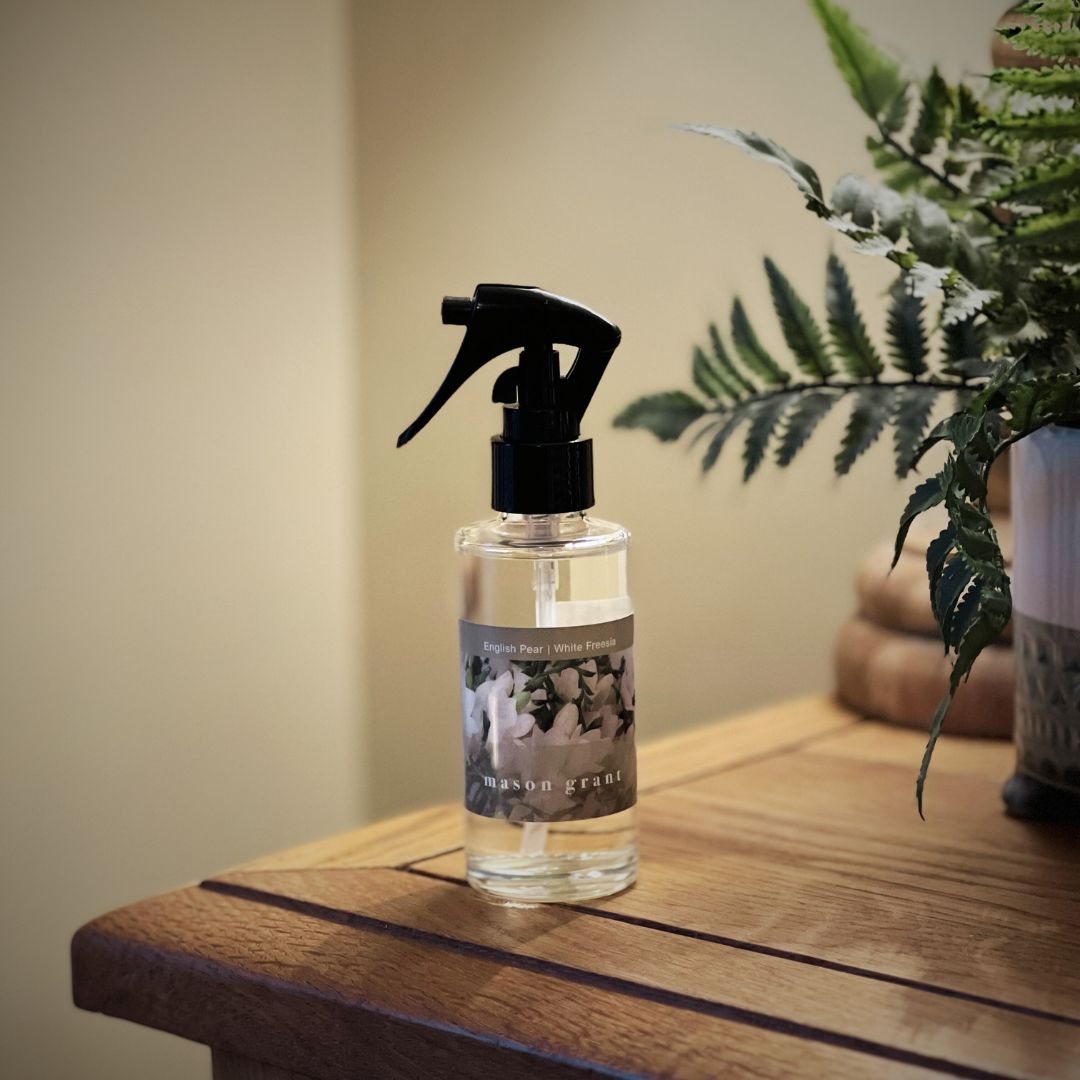 Mason Grant glass bottle room spray on wooden surface with greenery