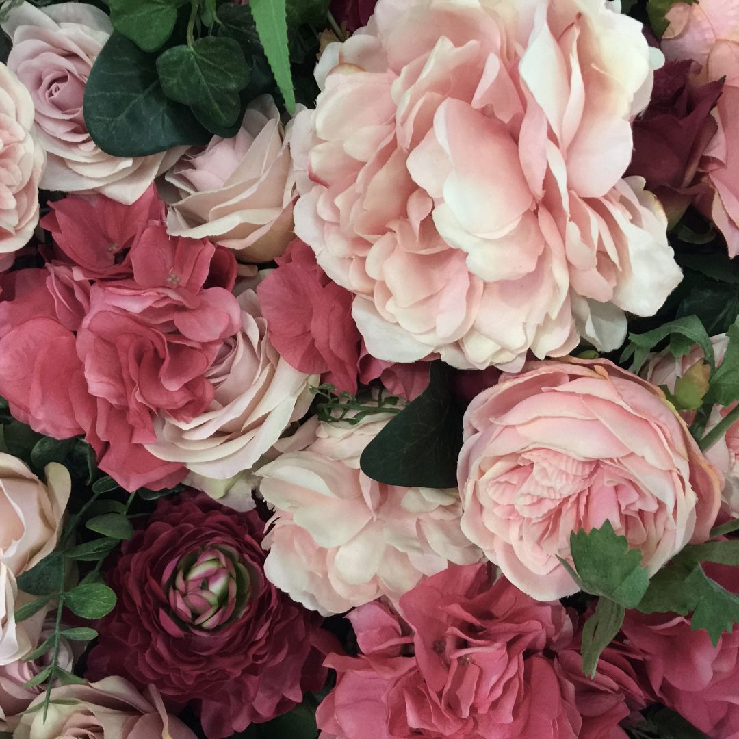 Close-up of a bouquet of pink and red flowers with green leaves.