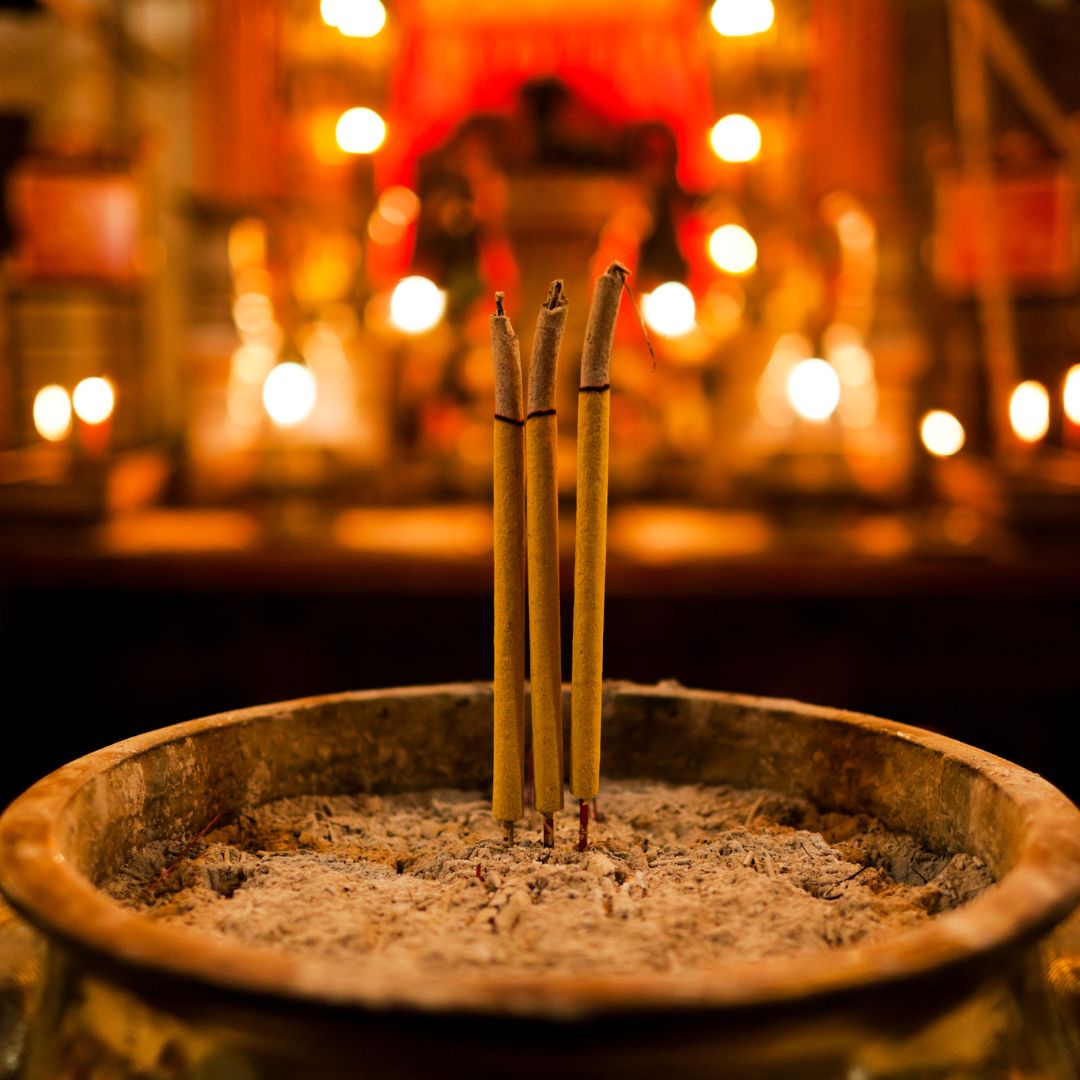 Incense sticks in a bowl with a blurred background of lights