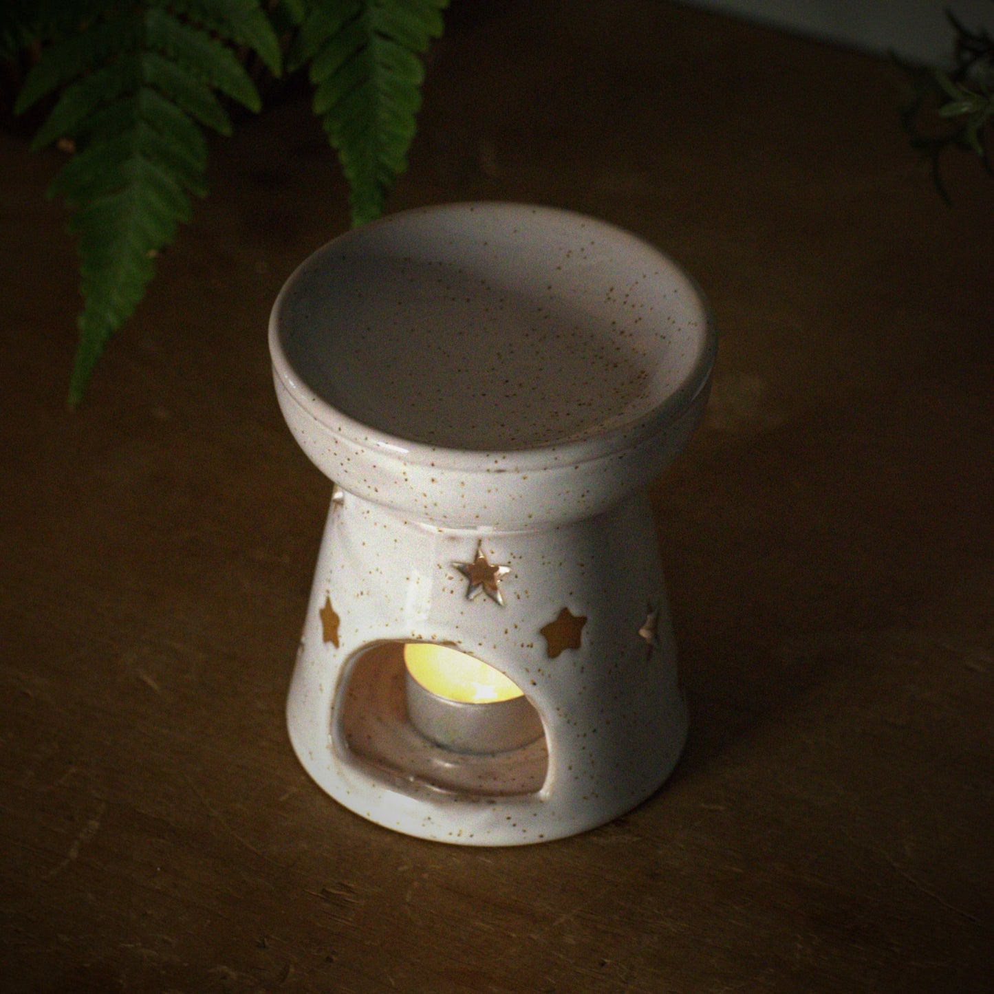 Ceramic wax and oil burner with star designs on a wooden surface