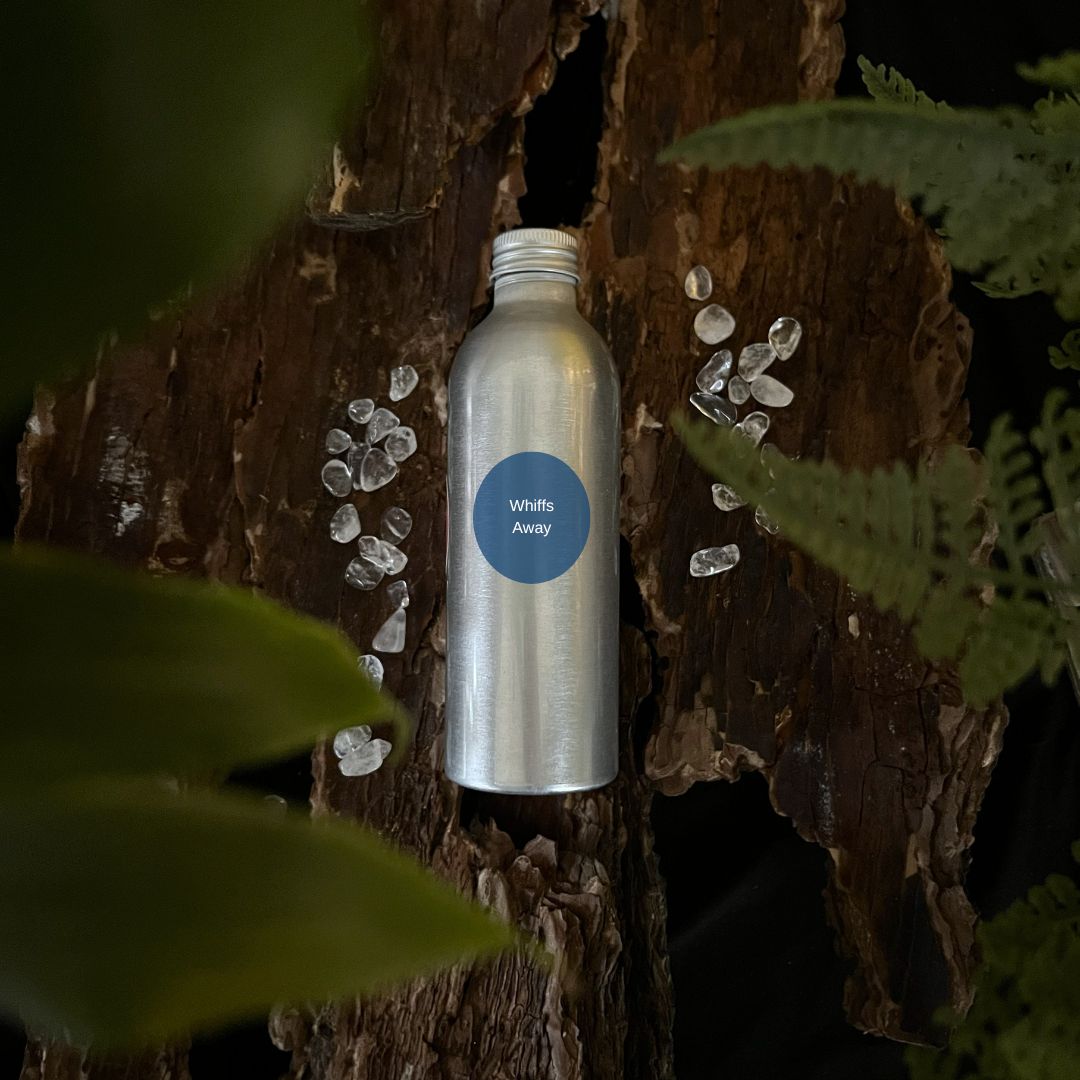 Aluminium Whiffs Away room spray refill bottle on a tree trunk with leaves in the foreground